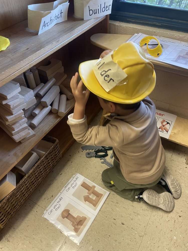 Pre-K student in a builder hat working in the blocks center