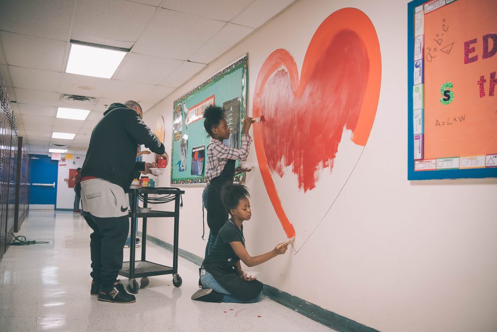 Students painting a heart mural in a school hallway